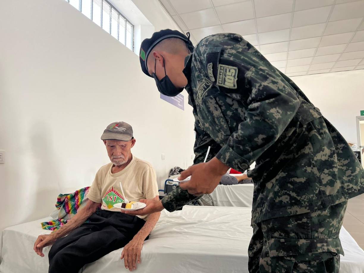 Un militar entrega pastel a uno de los abuelitos del hogar de ancianos.