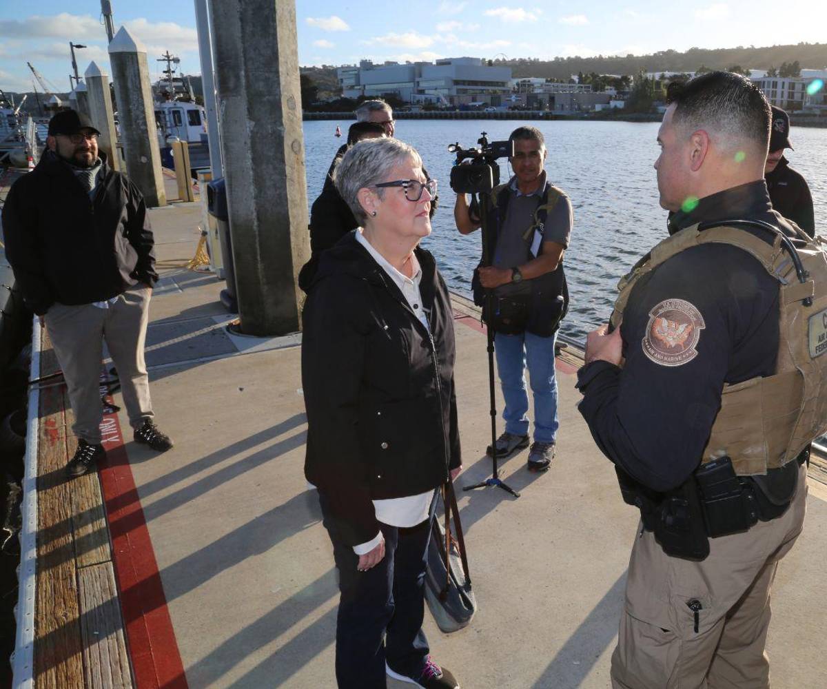 Lynne Walker conversa con un agente supervisor de Operaciones Aéreas y Marítimas durante un Programa de Cobertura de Inmigración en San Diego.