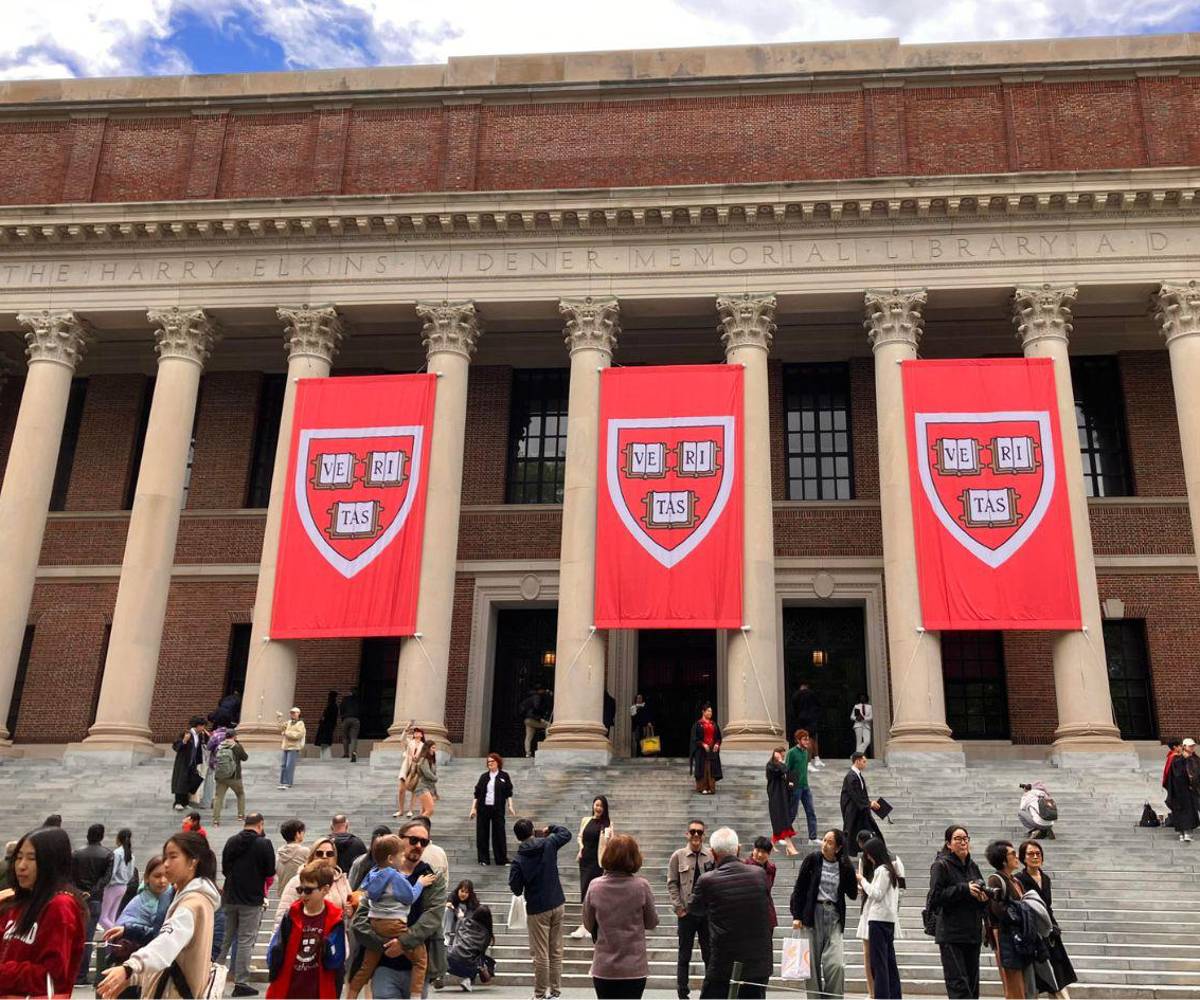 Personas caminan frente a la biblioteca de la Universidad de Harvard este lunes, en Boston (EE UU). El presidente estadounidense, Donald Trump, dijo que está valorando la posibilidad de retirar otros 3.000 millones de dólares en subvenciones para Harvard.