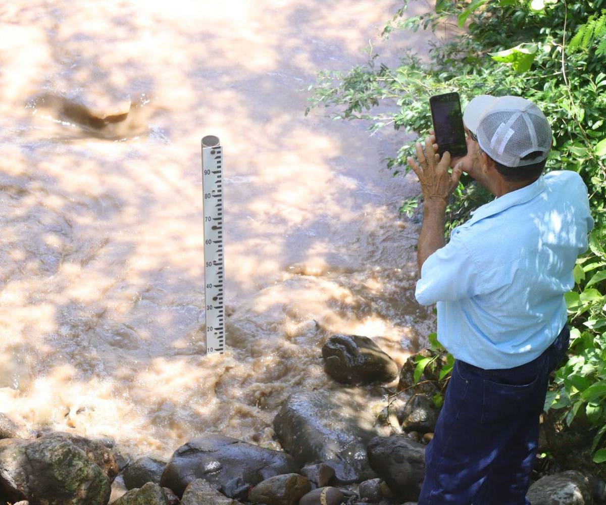 El poblador toma fotografías con su celular a los niveles del río para enviarlas a los técnicos.