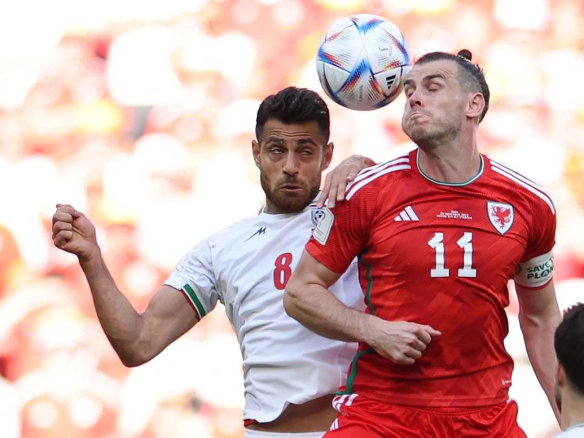 Gareth Bale saltando por la disputa del balón con el iraní Morteza Pouraliganji.