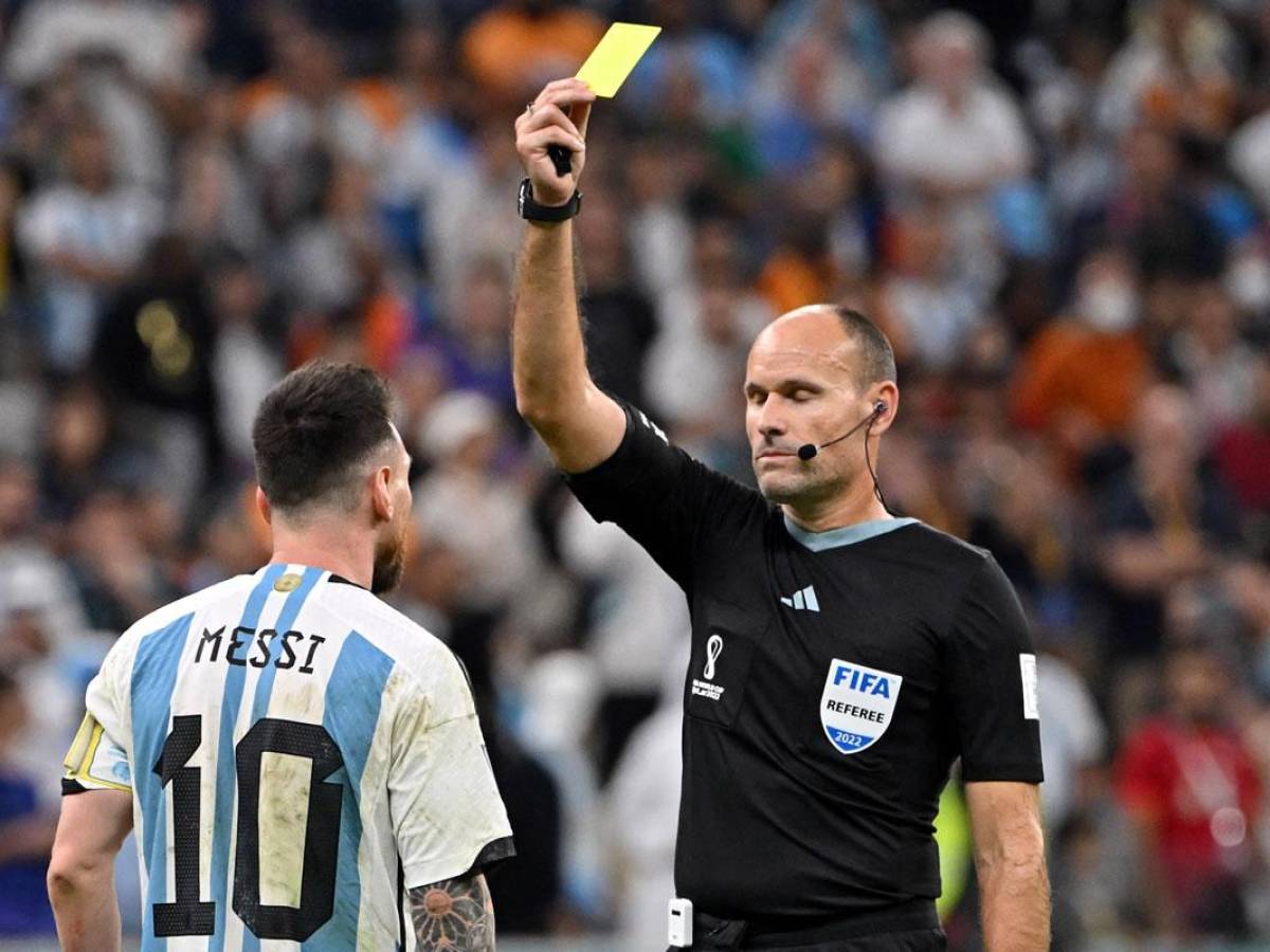 El árbitro Antonio Mateu Lahoz le muestra la tarjeta amarilla a Messi por reclamos.