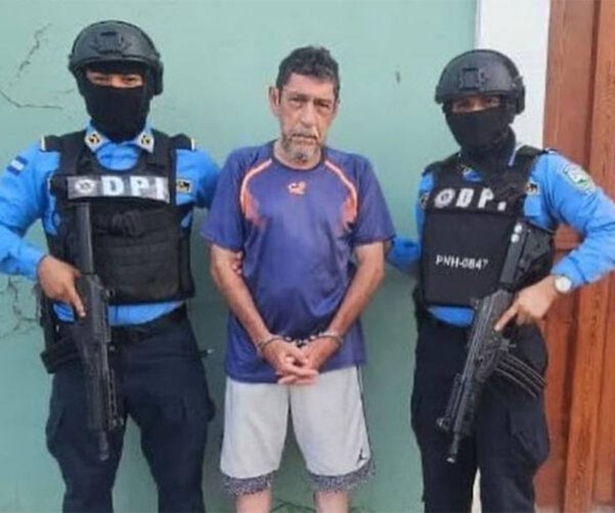 <i>En la fotografía aparece Perfecto Jesús Enamorado flanqueado por dos agentes de la Dirección Policial de Investigaciones (DPI) armados y encapuchados. Imagen tomada de las redes sociales el día de su captura. Foto: cortesía Proceso Digital.</i>