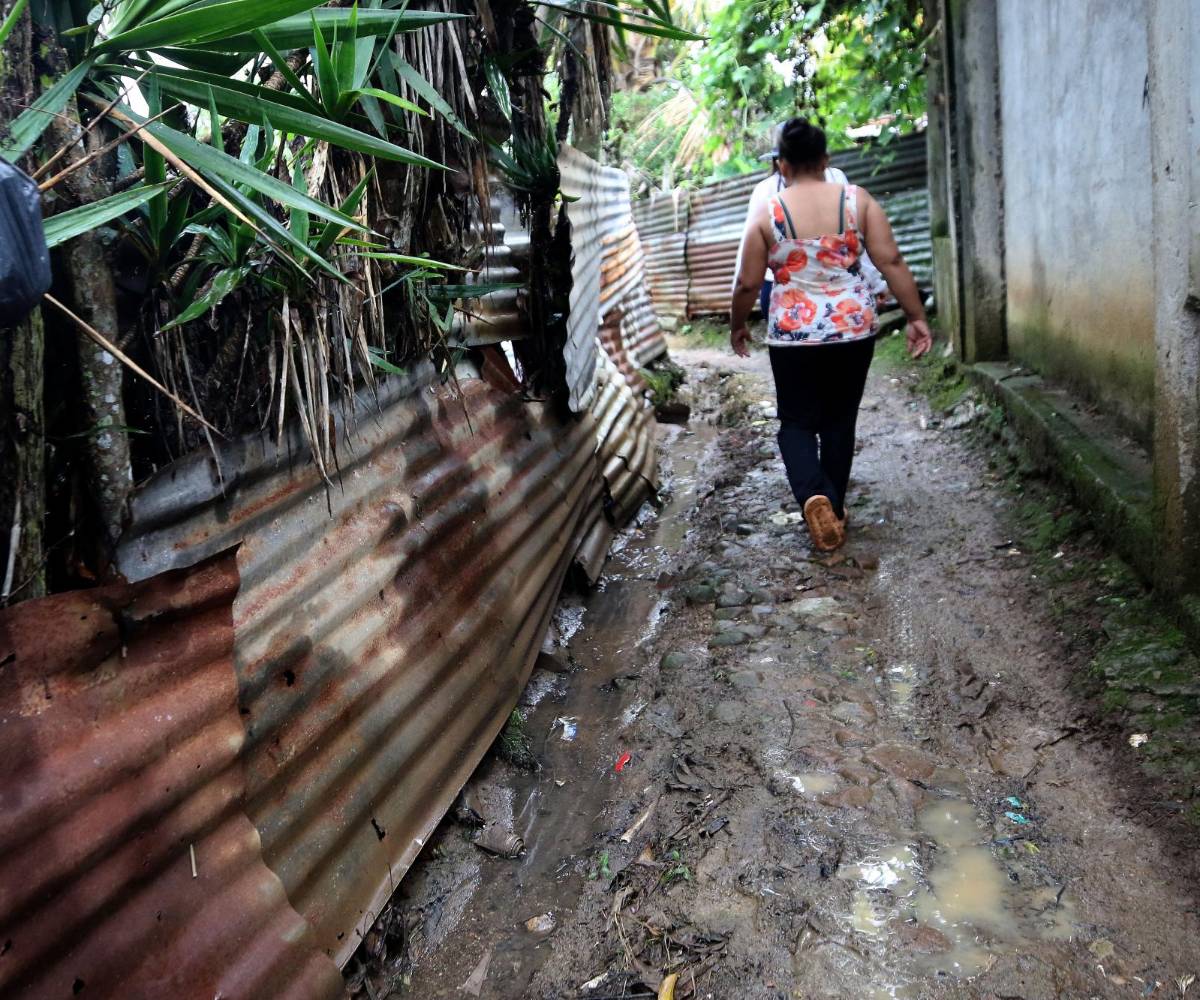 Una pobladora del municipio de Las Lajas, Comayagua, camina hacia la parte de atrás de su casa para mostrar cómo los sismos dejaron las paredes dañadas.