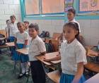 Estudiantes de un centro educativo público de pie mientras inician la clase.