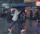 Una hondureña cruza un bulevar capitalino durante un día lluvioso.