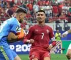 El portero Unai Simón de España se queda con el balón ante el acecho de Cristiano Ronaldo.