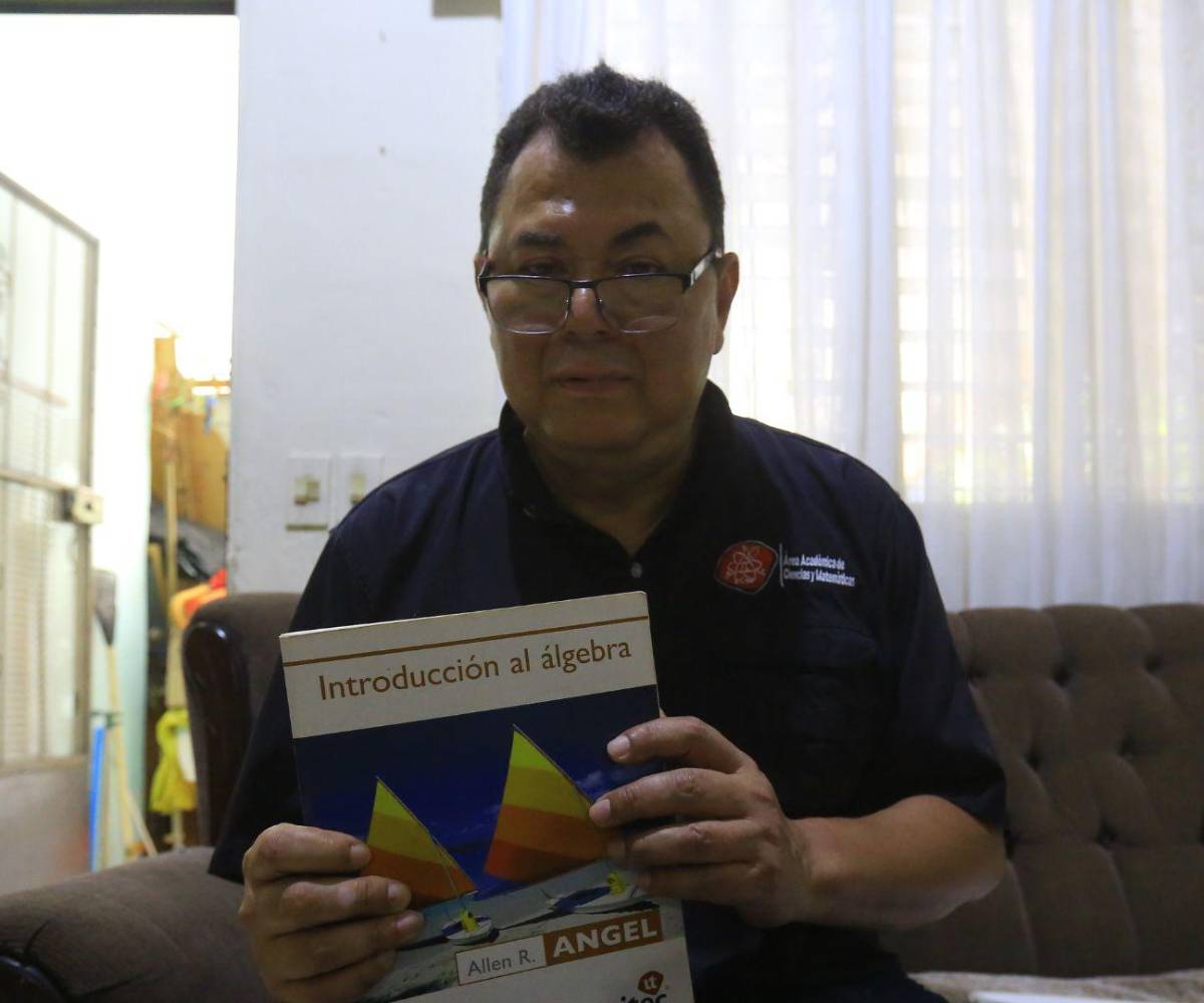 En esta imagen se aprecia al profesor sosteniendo un libro de álgebra, una de las herramientas adaptativas que facilitan su labor diaria.