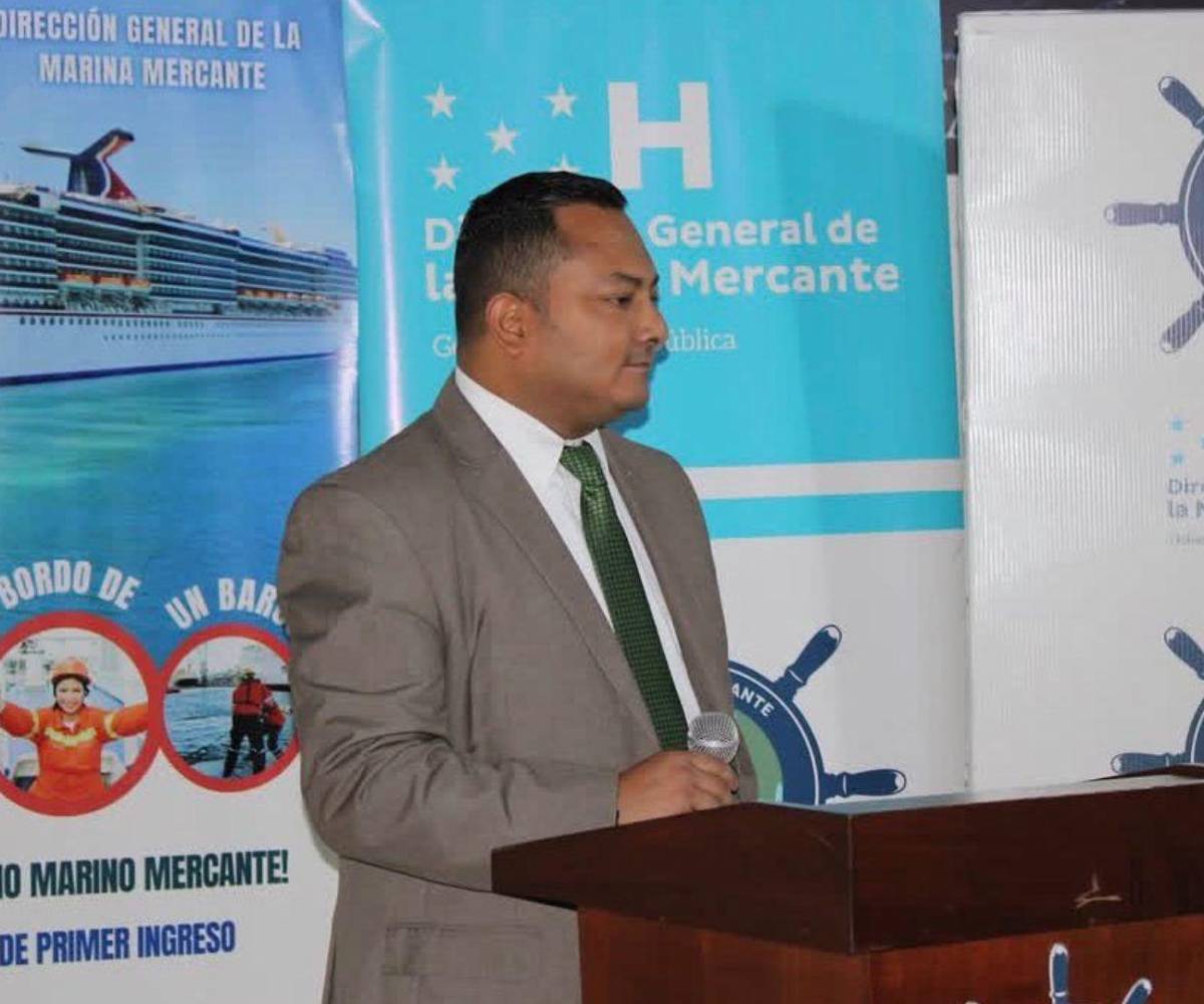 Néstor Rodríguez ofrece lo que parece ser una conferencia, con cartelas al fondo que muestran información propia de la Marina Mercante.