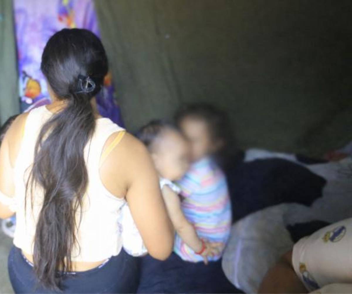 Ashley, de San Pedro Sula, sostiene a sus hijos mientras da testimonio de las dificultades de vivir sin servicios básicos.