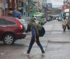 Un hondureño se protege de la lluvia en una calle de Tegucigalpa.