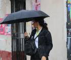 Una hondureña se protege de la lluvia en una calle de Tegucigalpa. Fotografía de archivo.