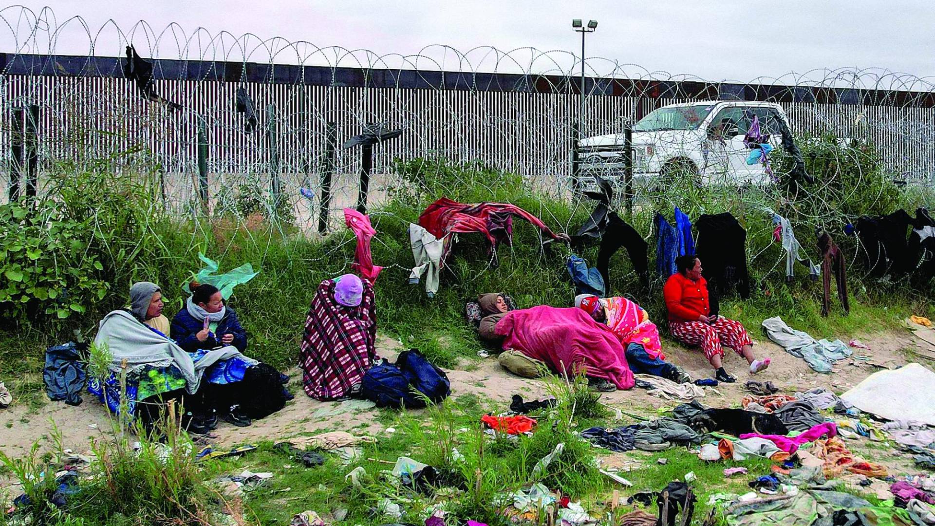 $!MEX994. CIUDAD JUÁREZ (MÉXICO), 05/11/2023.- Varios migrantes, visiblemente abrigados por las bajas temperaturas, permanecen a un costado del alambrado que marca la frontera con Estados Unidos, el 4 de noviembre de 2023, en Ciudad Juárez, estado de Chihuahua (México). La crisis humanitaria en la frontera norte de México se agudiza con el inicio de la temporada de frío, que ha provocado que miles de migrantes en Ciudad Juárez duerman a la intemperie o en refugios sin calefacción con temperaturas de hasta 3 grados. EFE/ Luis Torres