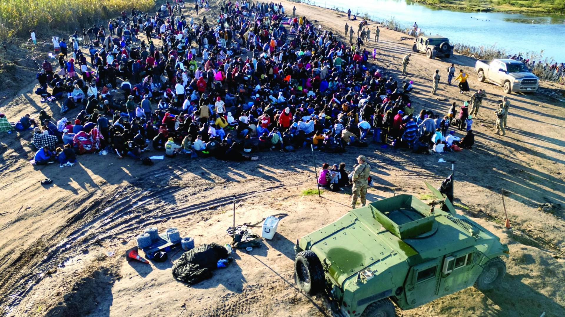 $!EAGLE PASS, TEXAS - DECEMBER 18: As seen from an aerial view Texas National Guard troops watch over some of more than 1,000 immigrants who had crossed the Rio Grande overnight from Mexico on December 18, 2023 in Eagle Pass, Texas. A surge as many as 12,000 immigrants per day crossing the U.S. southern border has overwhelmed U.S. immigration authorities in recent weeks. John Moore/Getty Images/AFP (Photo by JOHN MOORE / GETTY IMAGES NORTH AMERICA / Getty Images via AFP)