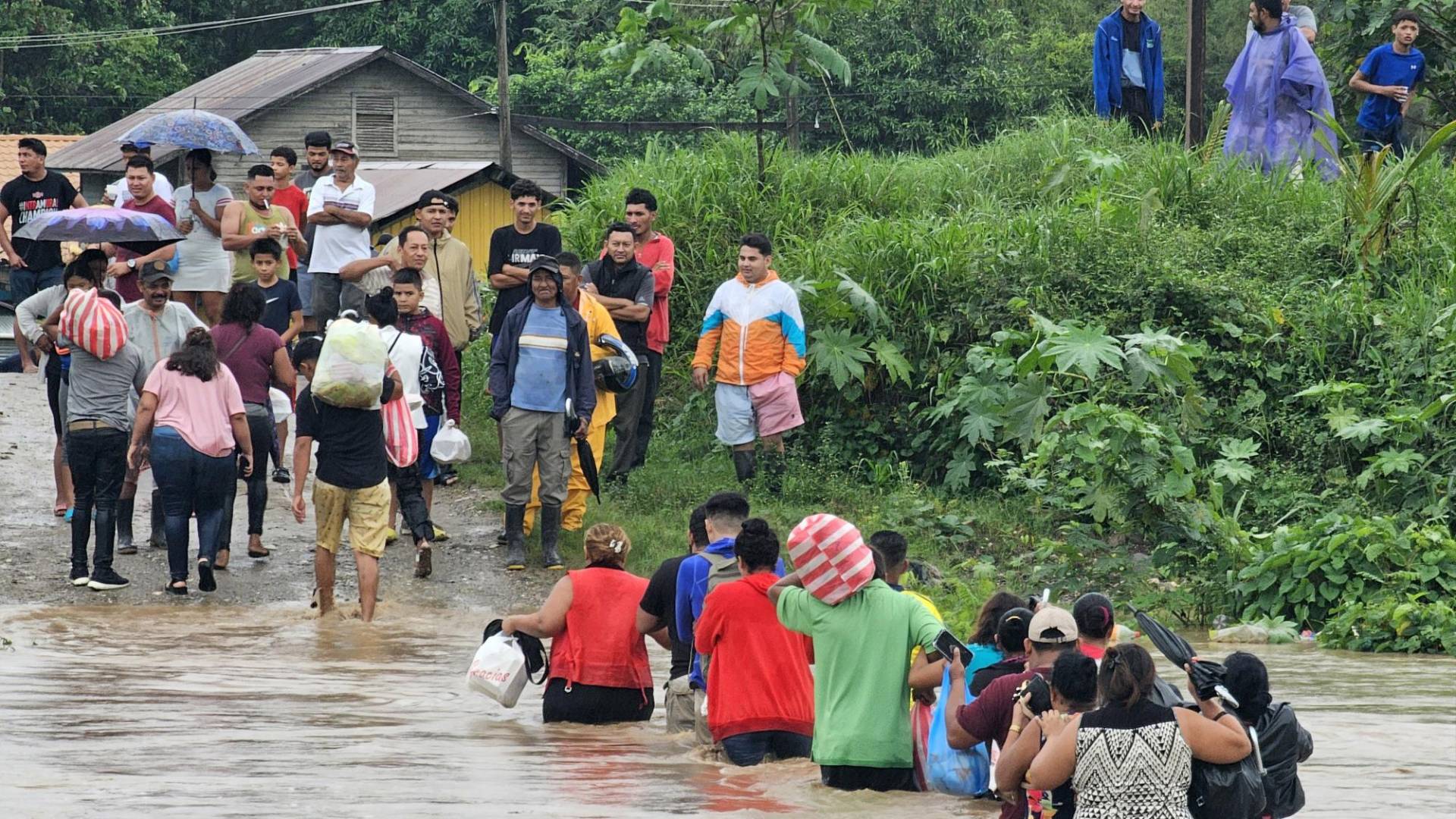 $!Habitantes de Campo Amapa, ubicado en la zona bananera de El Progreso, cruzan con sus pertenencias por un río en medio de las inundaciones causadas por la tormenta tropical Sara.