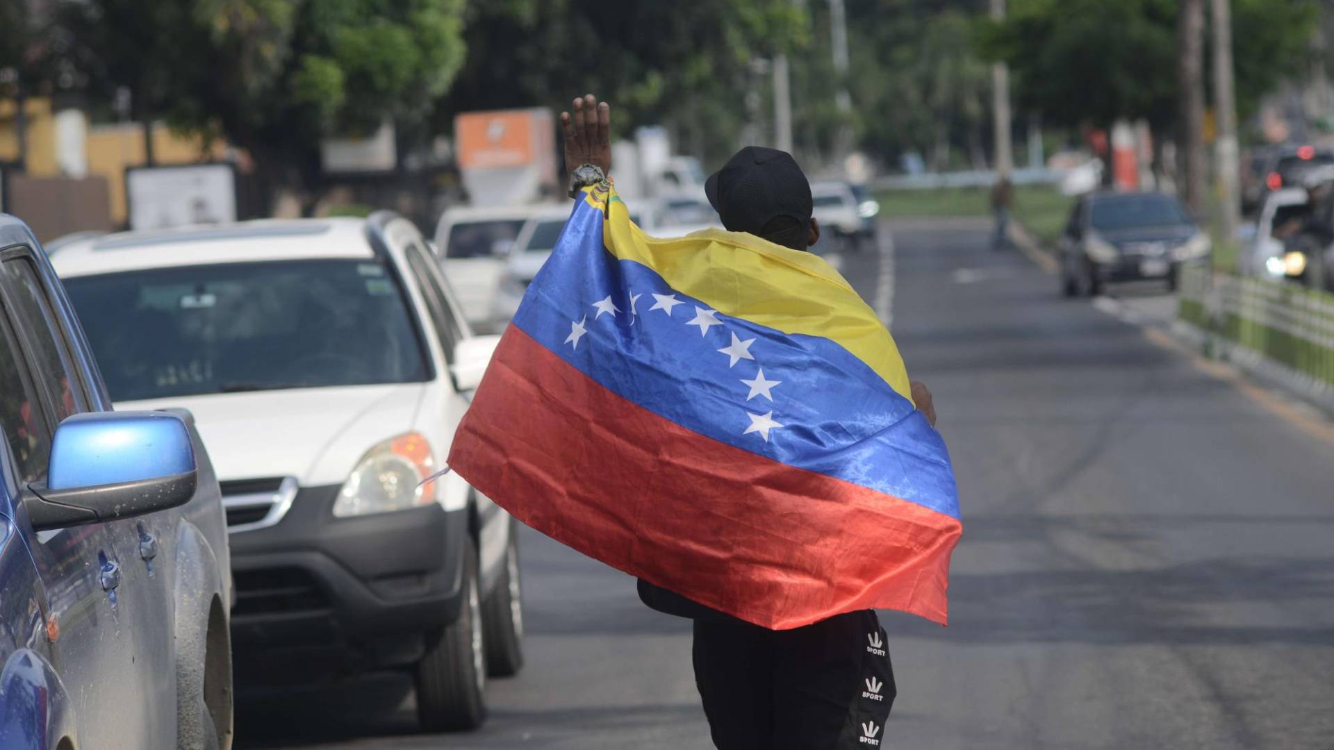 $!Migrante venezolano carga su bandera en una calle de San Pedro Sula.