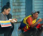 Dos venezolanos comen después de pedir en las calles de San Pedro Sula.