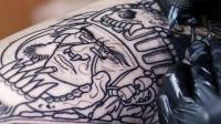 Una persona se tatúa un dibujo con tinta negra en una pierna.