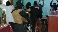 Agentes de la Dirección Policial Anti Maras y Pandillas Contra el Crimen Organizado (DIPAMPCO) revisan a unos hombres en un negocio de bebidas alcohólicas.