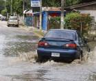 Vehículo turismo avanza por una calle inundada por las lluvias | Fotografía de archivo