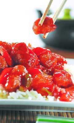 sweet and sour pork on rice being eaton with chopsticks