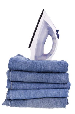 Stack of blue jeans and iron isolated on white background.