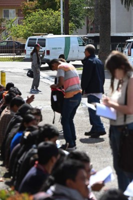 Volunteers assist Central American asylum seekers sitting outside the bus station in San Bernardino, California after they were brought their by U.S. Border Patrol vans, May 22, 2019. - For the last week Central American immigrant families have been brought by Border Patrol to the bus station 60 miles (97km) east of Los Angeles following processing. Volunteers wait at the bus station to help the families find transportation and shelter while they await their date in immigration court. (Photo by Robyn Beck / AFP)