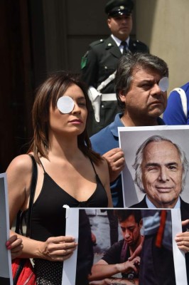 Health workers protest with portraits of Chilean former Interior Minister Andres Chadwich (R) and of a demonstrator whose eye reached by a police pellet, outside the Supreme Court of Justice in Santiago, on the fourth week of protests against the government of Chilean President Sebastian Pinera on November 11, 2019. - Chile has announced it will move to draft a new constitution and replace one dating back to the Augusto Pinochet dictatorship -- a key demand of protesters who have rocked the country for three weeks. (Photo by RODRIGO ARANGUA / AFP)