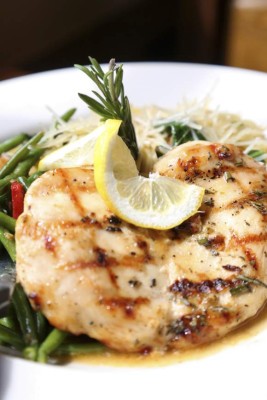 Italian Style grilled chicken on a bed of green beans and thin spaghetti with a sprig of Rosemary