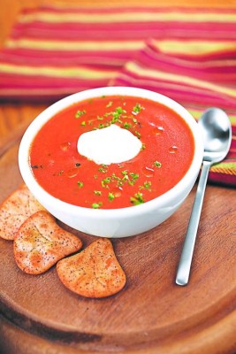 Tomato soup topped with herbs & sour cream and crackers. Shallow dof