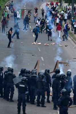 Riot police fire tear gas to disperse supporters of the Libertad y Refundacion (LIBRE) party in Tegucigalpa, on October 24, 2019, during a protest to demand Honduran President Juan Orlando Hernandez resignation for his alleged links to drug trafficking. (Photo by ORLANDO SIERRA / AFP)