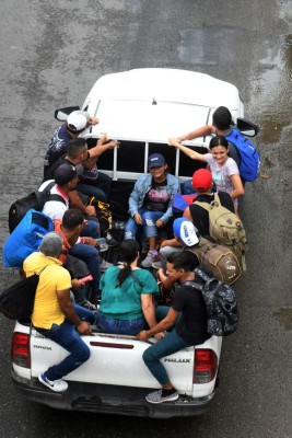 Honduran migrants ride in the back of a pickup truck as they leave the Metropolitan Center of San Pedro Sula, 300 kms north of Tegucigalpa, to travel to the Guatemala border on April 10, 2019. - Almost 1,000 people gathered Tuesday night in the town of San Pedro Sula in northern Honduras to form a new caravan to reach the United States, police said. Since October 13, when the first caravan of 2,000 set off, three other similar convoys of migrants have left Honduras for the US in search of work or fleeing drug-traffickers. (Photo by ORLANDO SIERRA / AFP)