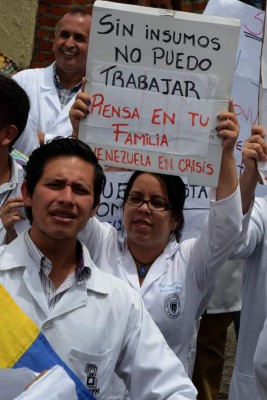 Medical personnel with a sign reading 'Without supplies I can't work. Think of your family. Venezuela in crisis', demonstrate in rejection of the policies conducted by the government of Venezuelan President Nicolas Maduro in the border town of San Cristobal on May 30, 2016.The shortage of medicines in Venezuela exceeds 85%, revealed the president of the farmaceutical federation of Venezuela, Freddy Ceballos. / AFP PHOTO / George Castellanos