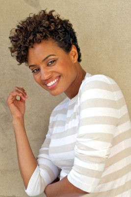 Portrait of happy young woman, aged 20 to 30 years, outdoors, stripey top, cream coloured background, some copy space