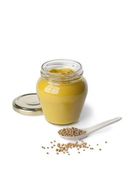 Mustard in a jar and mustard seeds on a spoon on white background