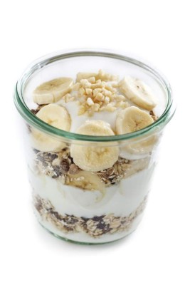 Glass with banana muesli and white background.