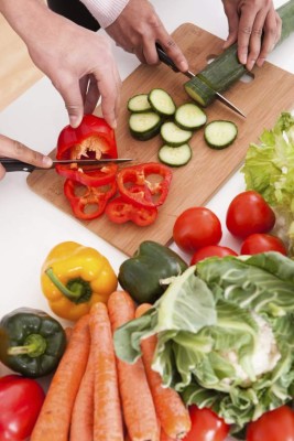 Portrait Of Couple Chopping Vegetables In Kitchen