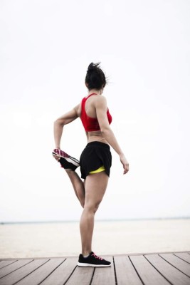 Young woman stretching on the beach after running, Dubai, Jumeirah Beach