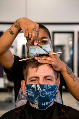 Hair stylist Jade Thanars gives a hair cut to a client, both wearing facemasks, at Fifi Mahoney's Bywater Beauty Parlor, on the first day of New Orleans' reopening Phase 1, after two months of closures due to the novel coronavirus pandemic, in New Orleans, on May 16, 2020. - New Orleans began allowing some businesses to reopen with restrictions. (Photo by Claire BANGSER / AFP)