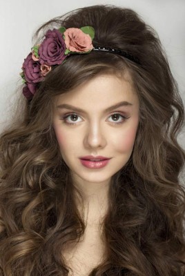 Beautiful smiling thoughtful woman with curly hair posing at studio