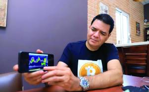 Erick Andrade muestra en su celular las alzas y las bajas del precio del bitcóin. Foto : Melvin Cubas.