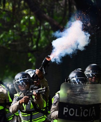 Riot police fire tear gas grenades and rubber bullets at a march of students from the public Central University of Venezuela demanding a referendum on removing President Nicolas Maduro, in Caracas on June 9, 2016. / AFP PHOTO / RONALDO SCHEMIDT
