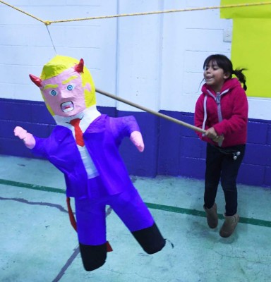 A girl hits a pinata with the figure of US President Donald Trump during a traditional posada in Mexico City, on December 16, 2017.The Posadas is a Catholic ritual that reenacts Mary and Joseph's journey from Nazareth to Bethlehem in search of a birth place for the Christ Child. / AFP PHOTO / PEDRO PARDO