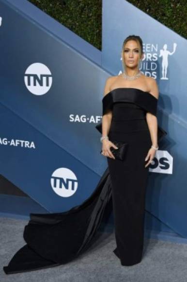 Jennifer López súper elegante en un vestido negro con cola.