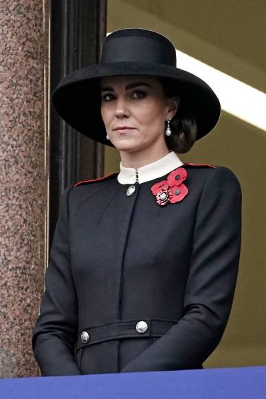 Para el evento, Kate optó por un abrigo negro de Alexander McQueen con solapas rojas, cuello blanco y detalle de botones plateados, que ya había utilizado en otro evento hace dos años. La duquesa acompañó su atuendo con un sombrero negro que recordó a uno utilizado por la princesa Diana durante su última participación en el homenaje a los caídos.