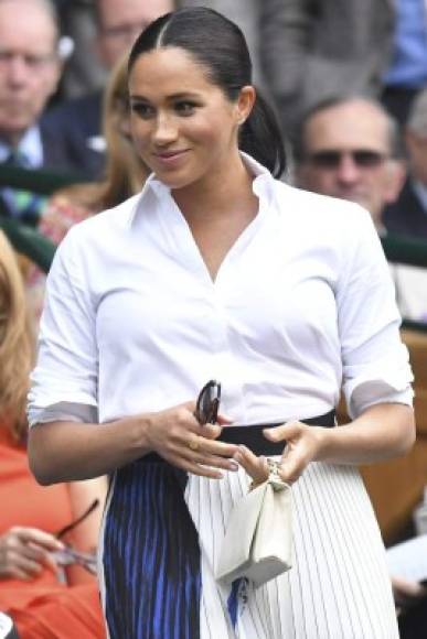 A diferencia de su último look en un juego de tenis, Meghan Markle optó por seguir el 'código de vestimenta' (el público mantiene la costumbre de asistir con ropa formal) y llegó con una camisa blanca y una falda plisada a tono con detalles en azul de Hugo Boss.