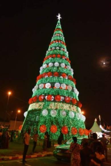 La gente camina junto a un árbol de Navidad iluminado con los colores de la bandera nacional de Costa de Marfil.