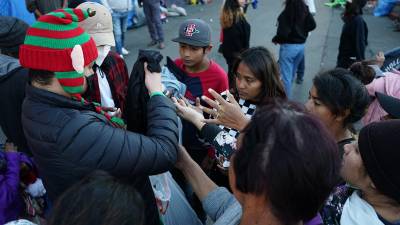 Voluntarios entregan regalos a migrantes centroamericanos en las afueras de un albergue en Tijuana.