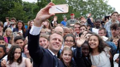 Emmanuel Macron se fotografía con un grupo de jóvenes durante el acto conmemorativo. Foto. EFE