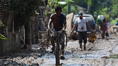 Un hombre anda en bicicleta tras el paso del huracán Eta en el barrio Omonita en El Progreso, Yoro.